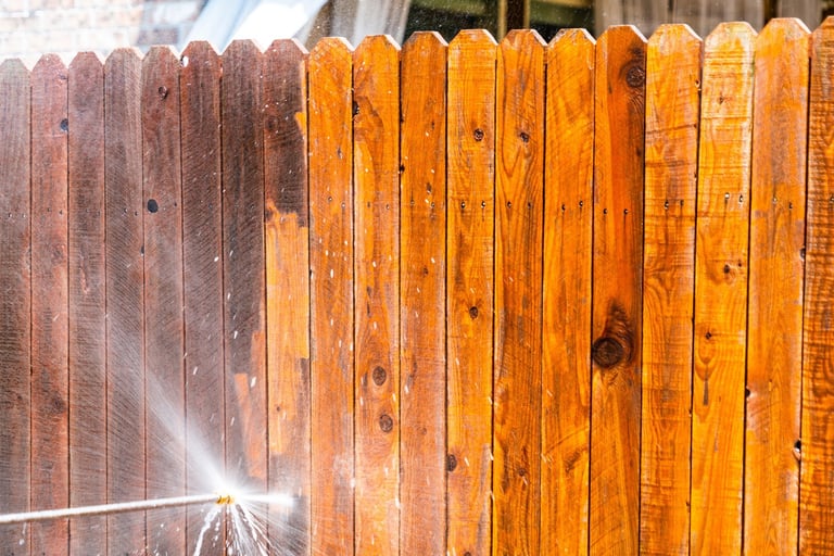 Pressure washing old dirty wooden fence — showing the before state with gray weathered planks